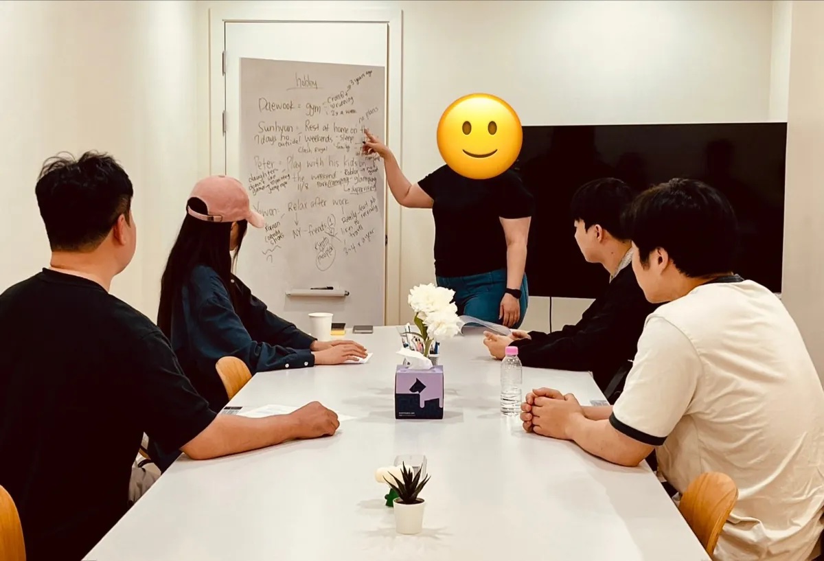 화이트보드 앞에서 강사가 설명하고 수강생 네 명이 긴 테이블에 앉아 듣는 소그룹 수업